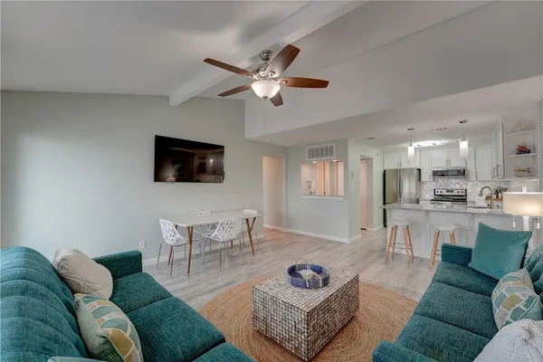 a living room with furniture a flat screen tv and kitchen view
