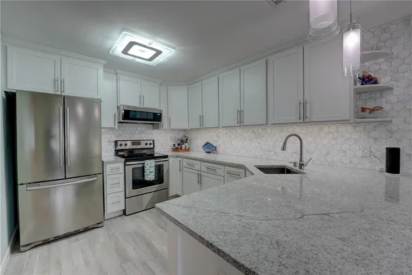 a kitchen with granite countertop a refrigerator stove and sink