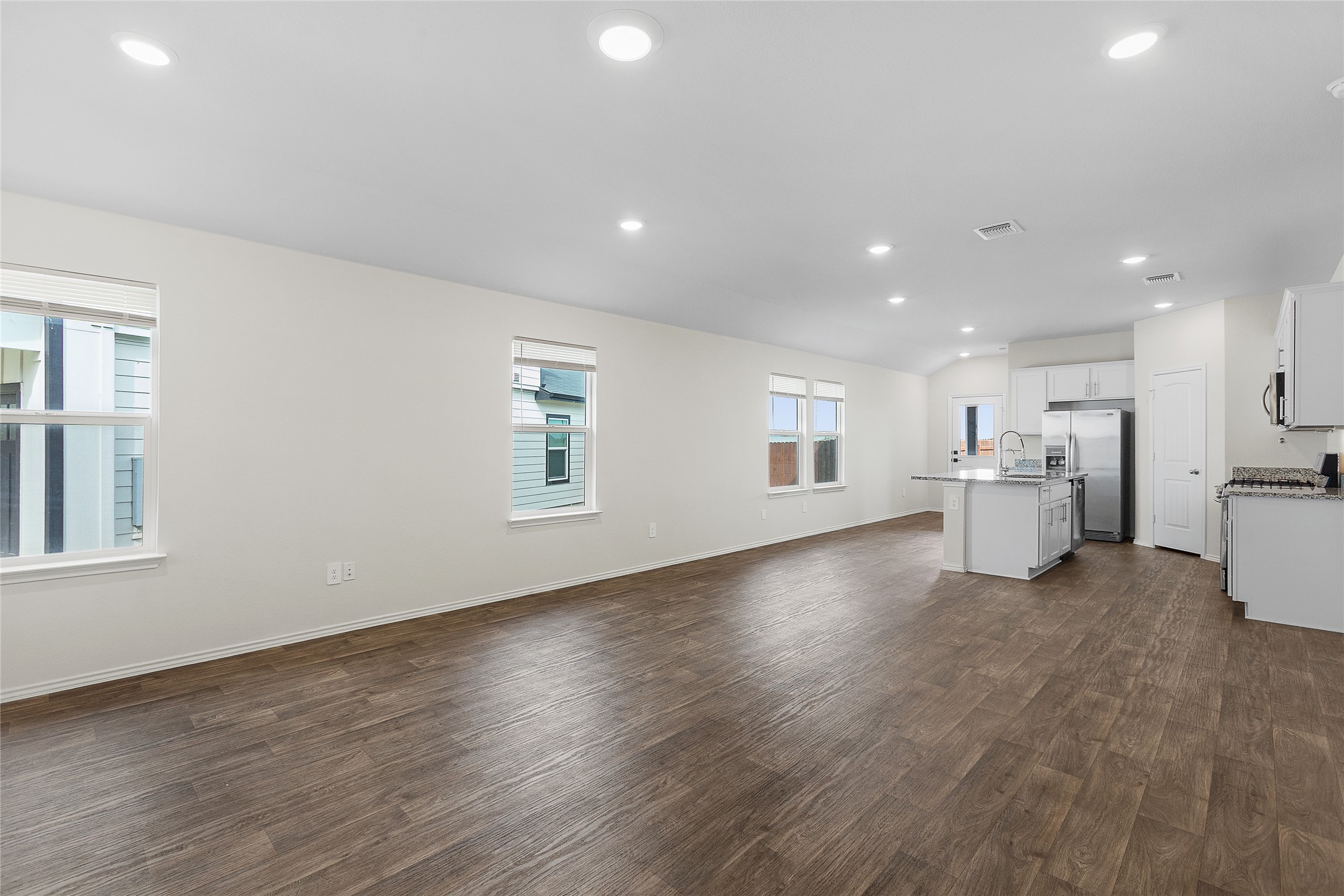 An open-concept layout unites a pristine kitchen with a spacious living area, ideal for modern living.