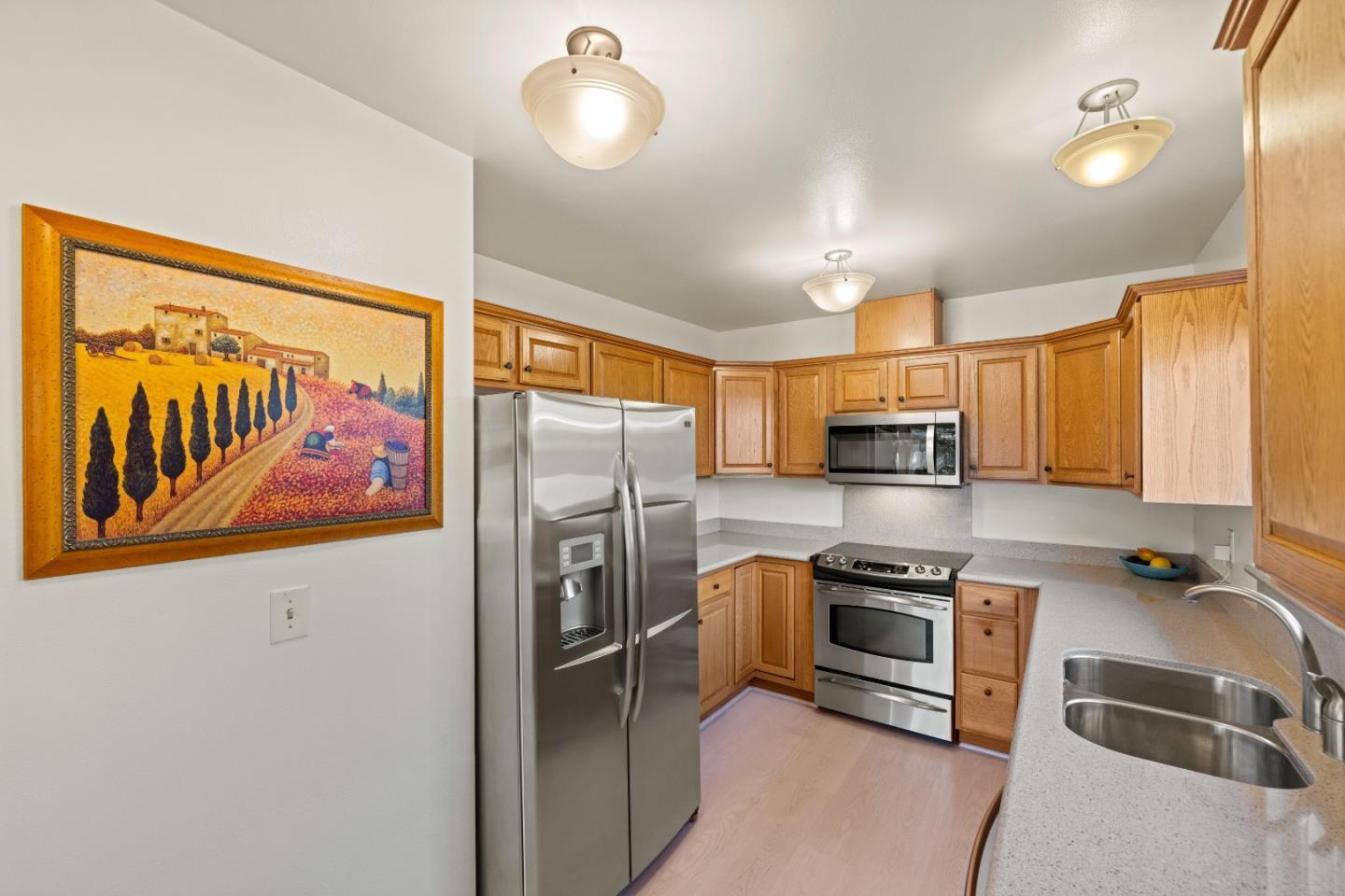 902 Maple Street Pacific Grove, CA 93950 - Photo 14 of 35 a kitchen with stainless steel appliances granite countertop a refrigerator a stove and a sink with wooden floor