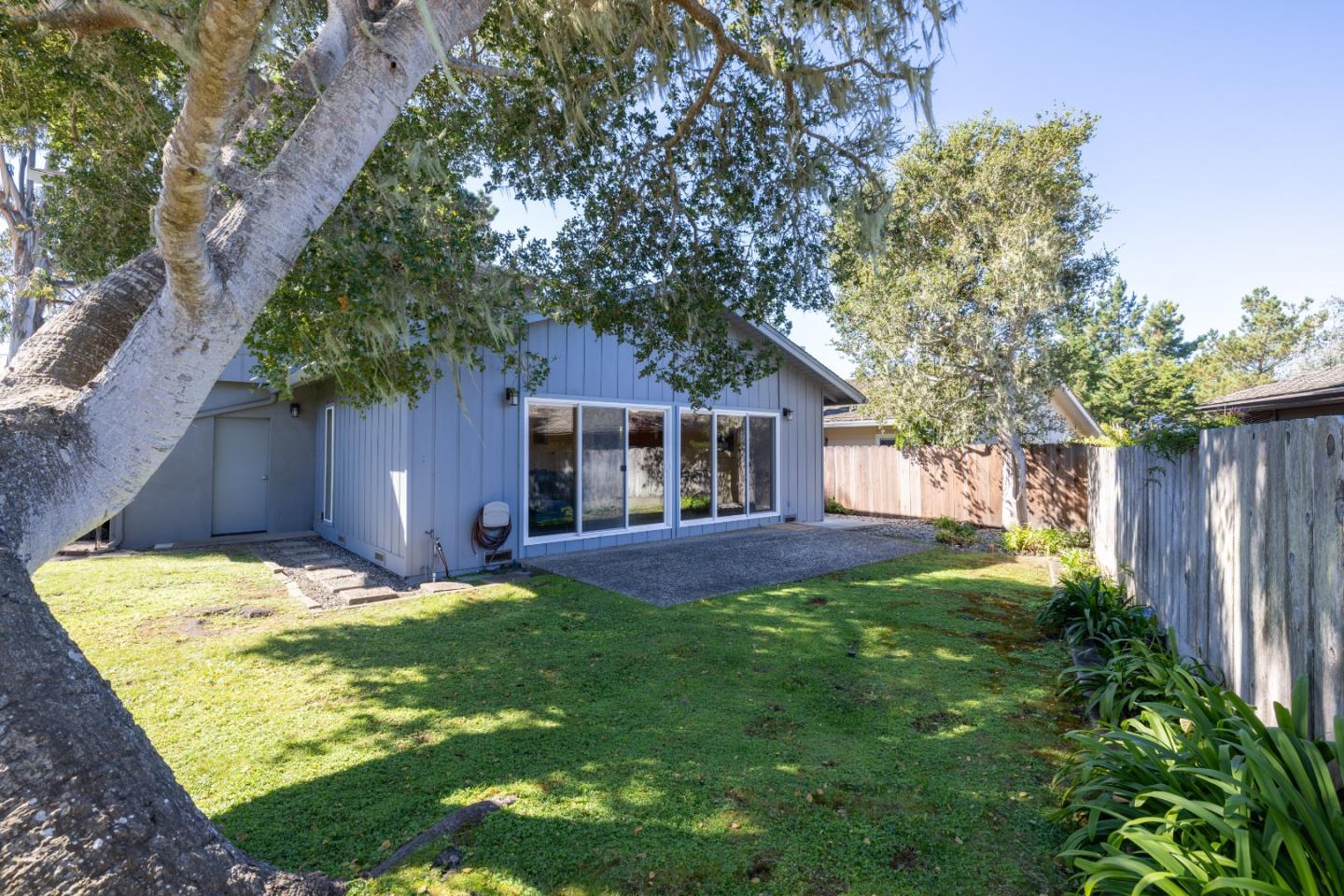902 Maple Street Pacific Grove, CA 93950 - Photo 29 of 35 a backyard of a house with table and chairs plants and large tree