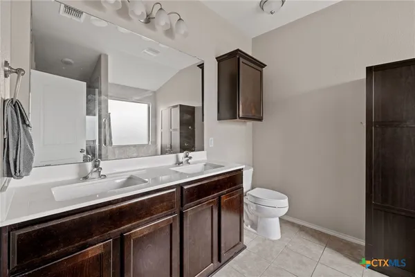 a bathroom with a granite countertop toilet sink and mirror