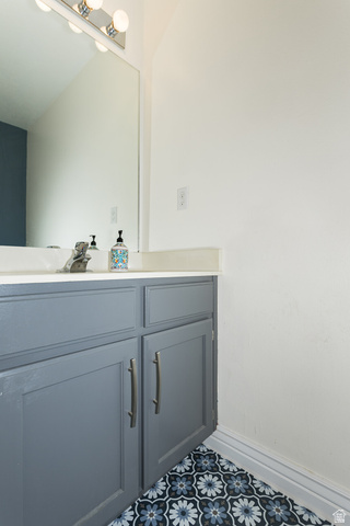 7797 North Windhover Road Eagle Mountain, UT 84005 - Photo 13 of 33 Bathroom vanity featuring grey cabinetry, white countertop, and patterned floor tiling