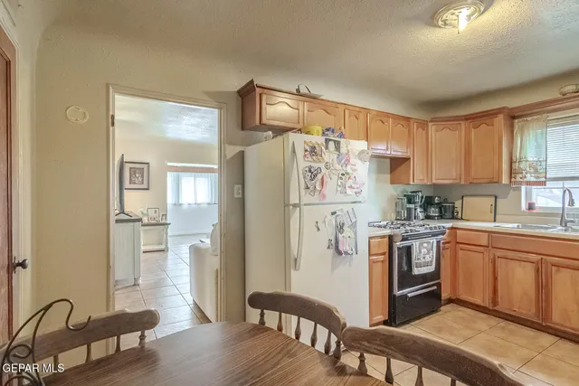 a kitchen with stainless steel appliances granite countertop a refrigerator a sink dishwasher a stove with white cabinets and wooden floor