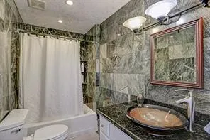 a bathroom with a granite countertop sink toilet and shower