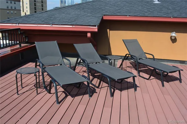 a view of a chairs and table on the wooden roof deck