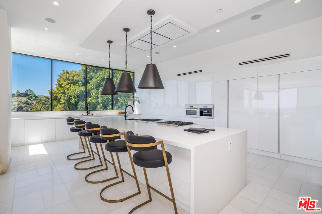 9406 Lloydcrest Drive Beverly Hills, CA 90210 - Photo 17 of 52 a kitchen with stainless steel appliances a table and chairs in it