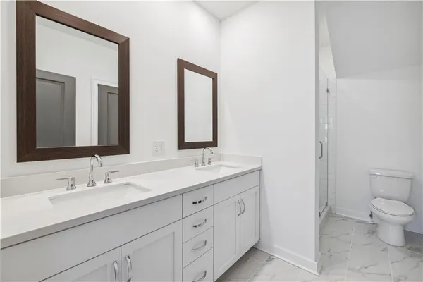 a bathroom with double sink a toilet and a mirror