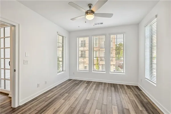 a view of an empty room with wooden floor and a window