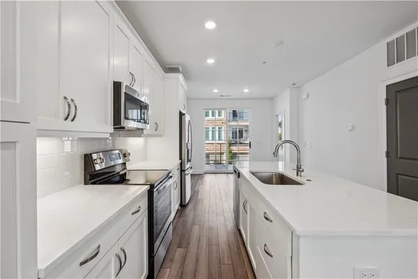 a kitchen with stainless steel appliances a sink a stove a microwave a sink a refrigerator and cabinets