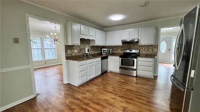 a kitchen with stainless steel appliances granite countertop a stove top oven a sink and white cabinets