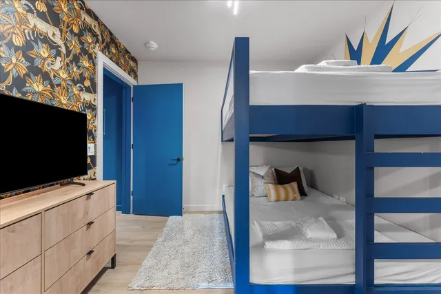 a bedroom with a bed and a flat tv screen on dresser