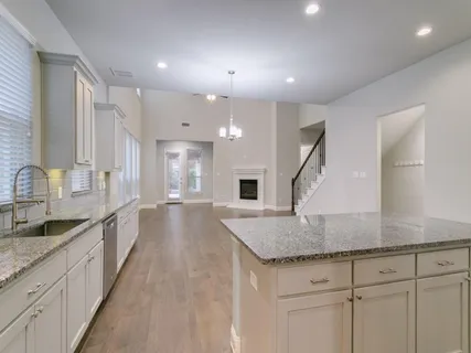 a large kitchen with kitchen island a large counter top a sink and stainless steel appliances