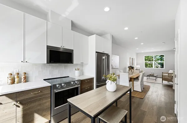a kitchen with stainless steel appliances a dining table chairs stove and refrigerator