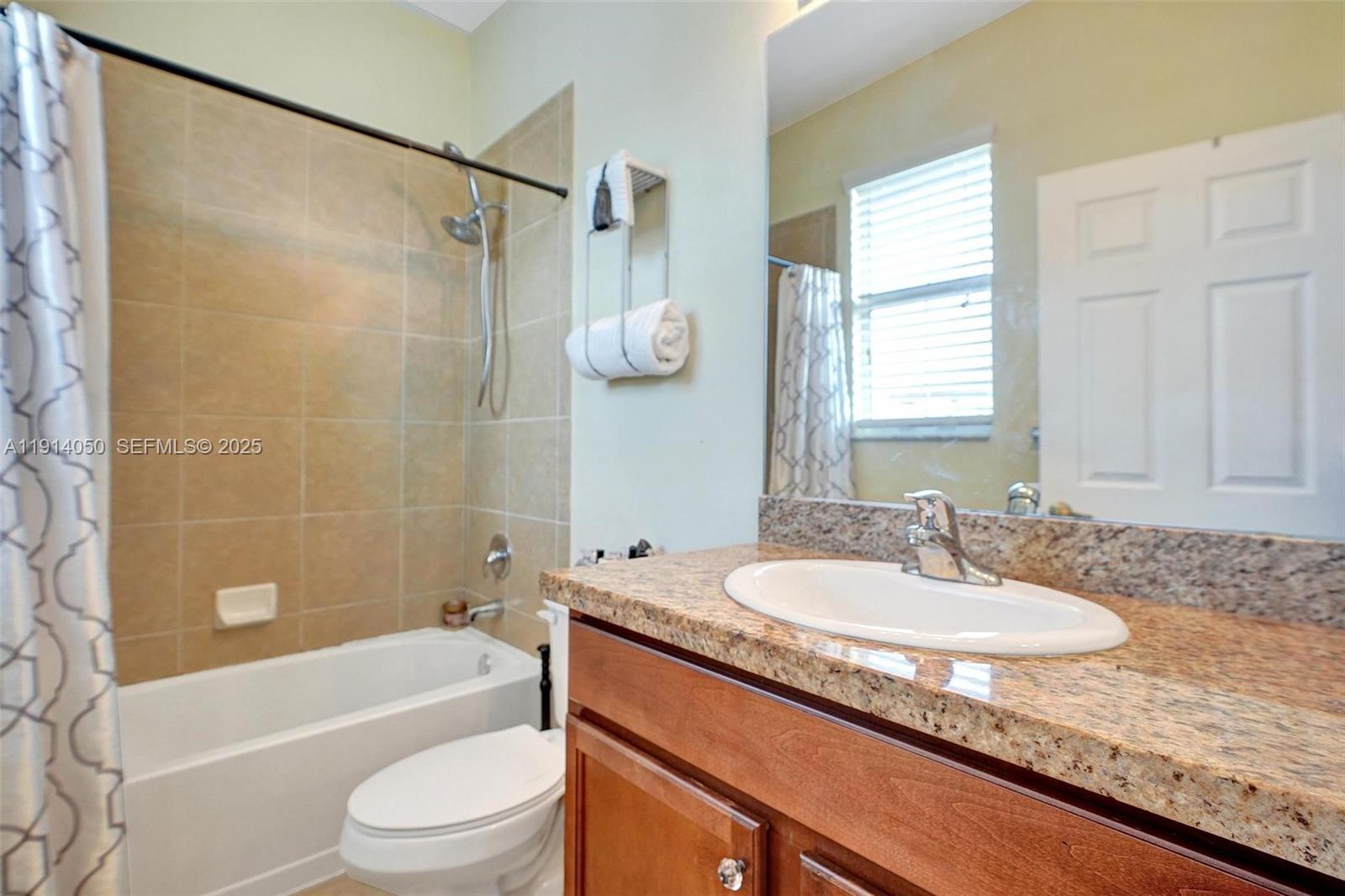 2659 Southwest 118 Road Miramar, FL 33025 - Photo 20 of 28 a bathroom with a granite countertop sink a toilet a mirror a bathtub and shower