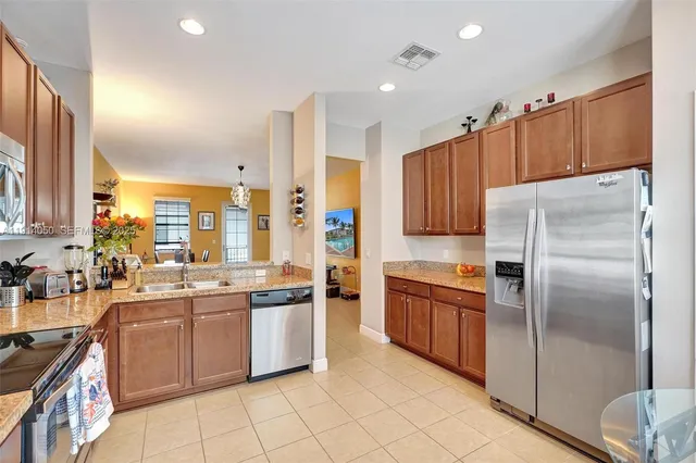 a kitchen with stainless steel appliances granite countertop a refrigerator a sink a stove a washer and dryer