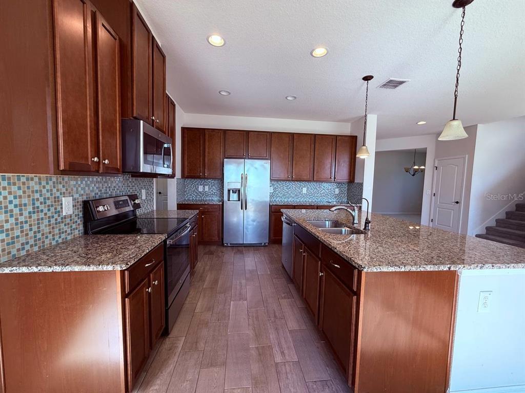 14112 Poke Ridge Drive Riverview, FL 33579 - Photo 6 of 32 a large kitchen with stainless steel appliances granite countertop a stove a sink and a granite counter tops