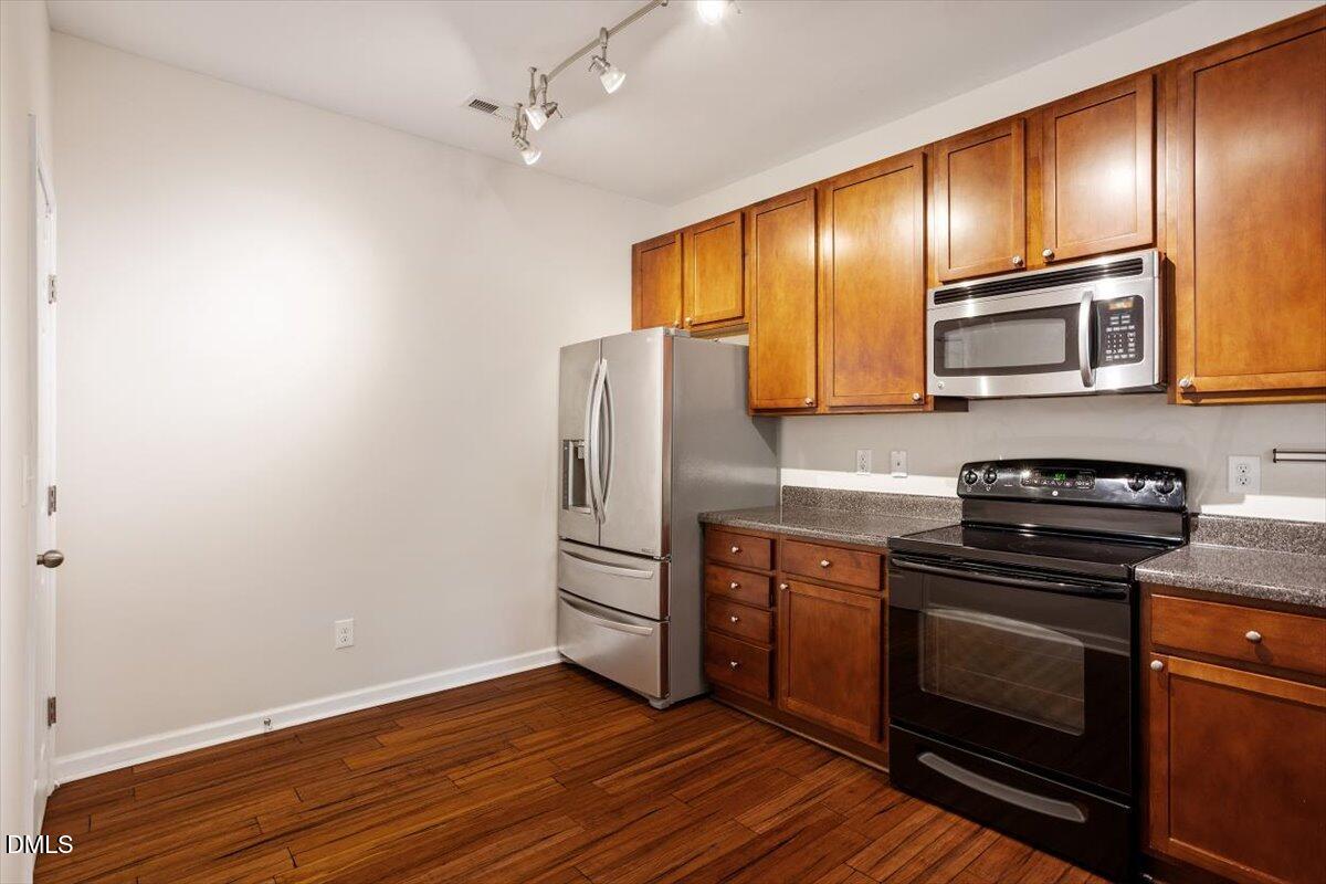 1120 Renewal Place, Unit 113 Raleigh, NC 27603 - Photo 4 of 38 a kitchen with granite countertop wooden cabinets stainless steel appliances and a wooden floor