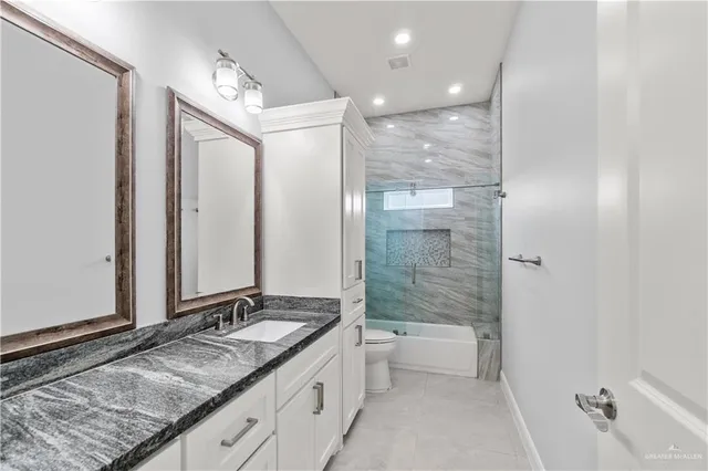 a bathroom with a granite countertop sink mirror and a bathtub