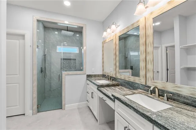 a bathroom with a granite countertop double vanity and a mirror