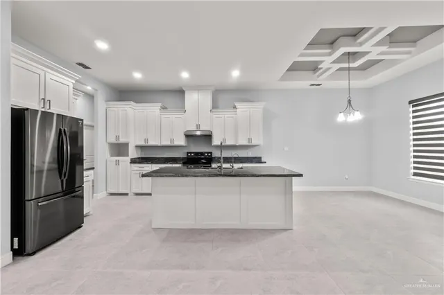 a kitchen with stainless steel appliances granite countertop a refrigerator a sink dishwasher a stove and white cabinets