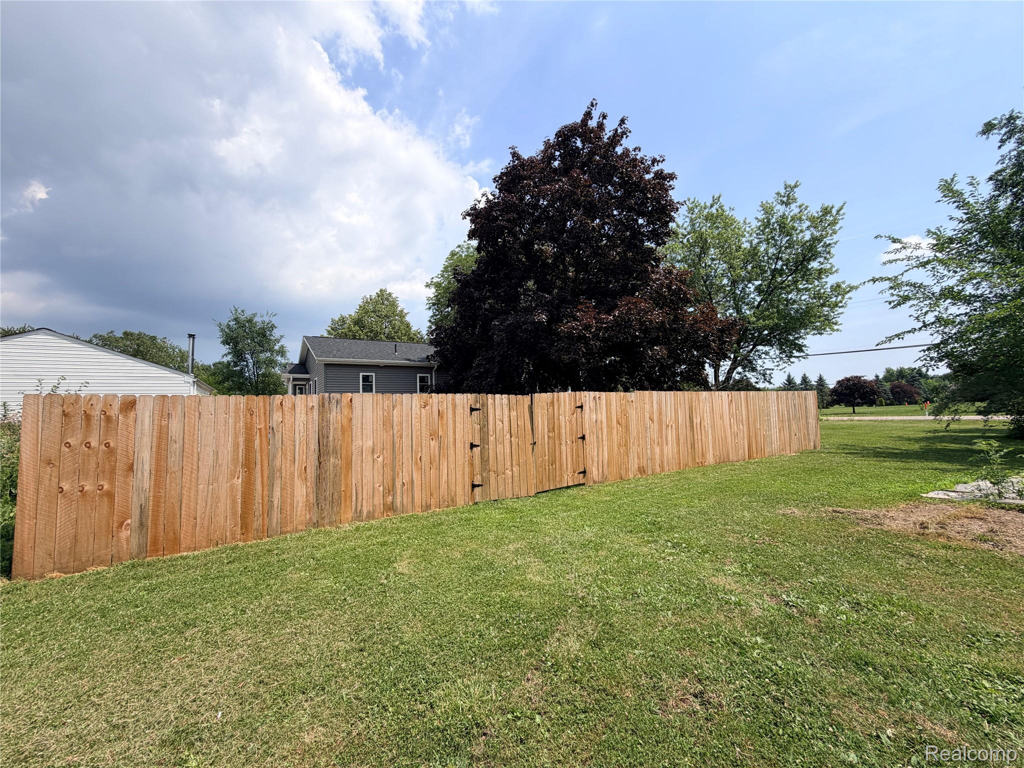 3840 East Dunbar Road Monroe, MI 48161 - Photo 9 of 38 Wood privacy fence featuring a double gate, surrounding a grassy yard with mature trees