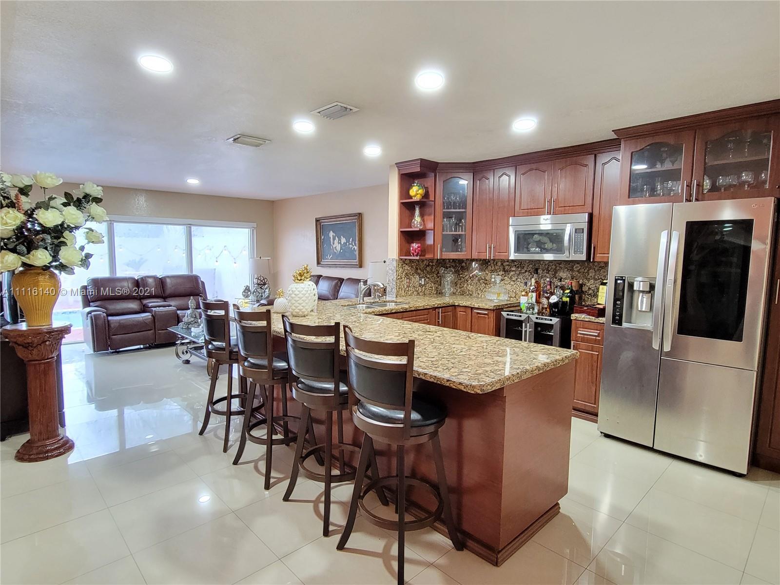 12989 Southwest 251st Terrace Homestead, FL 33032 - Photo 7 of 28 a kitchen with stainless steel appliances kitchen island granite countertop a table chairs and a refrigerator