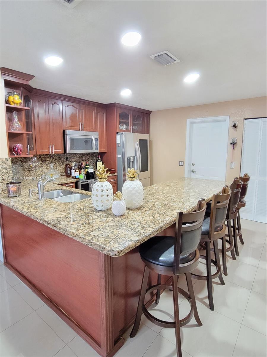 12989 Southwest 251st Terrace Homestead, FL 33032 - Photo 8 of 28 a kitchen with kitchen island granite countertop wooden cabinets a counter top space and stainless steel appliances