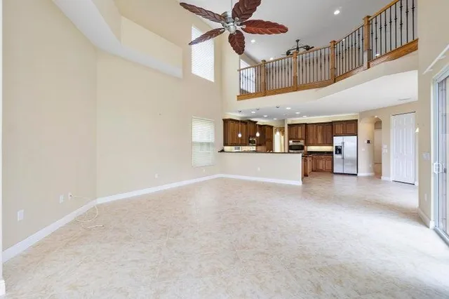 an empty room with chandelier fan and windows