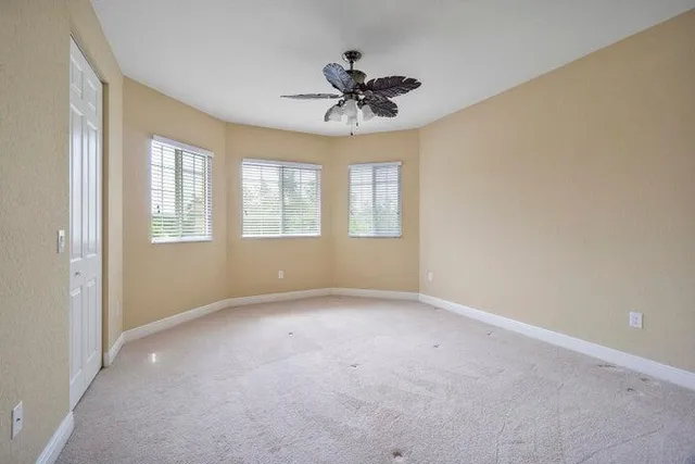 an empty room with windows and ceiling fan