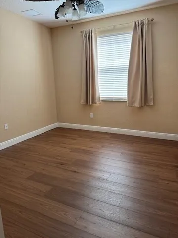 a view of a white house with a yard and palm trees