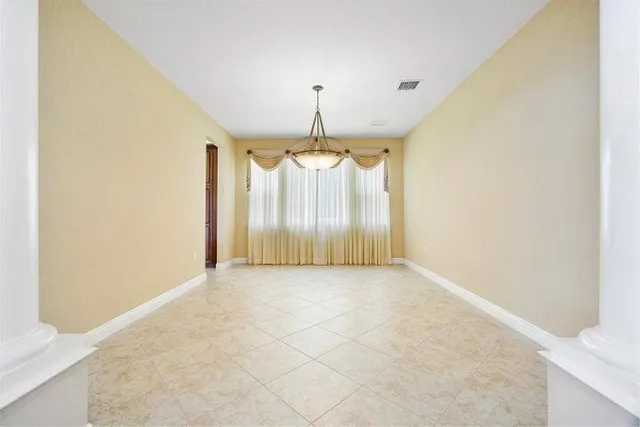 an empty room with chandelier fan and refrigerator