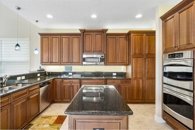 a kitchen with stainless steel appliances granite countertop a stove a sink and a microwave