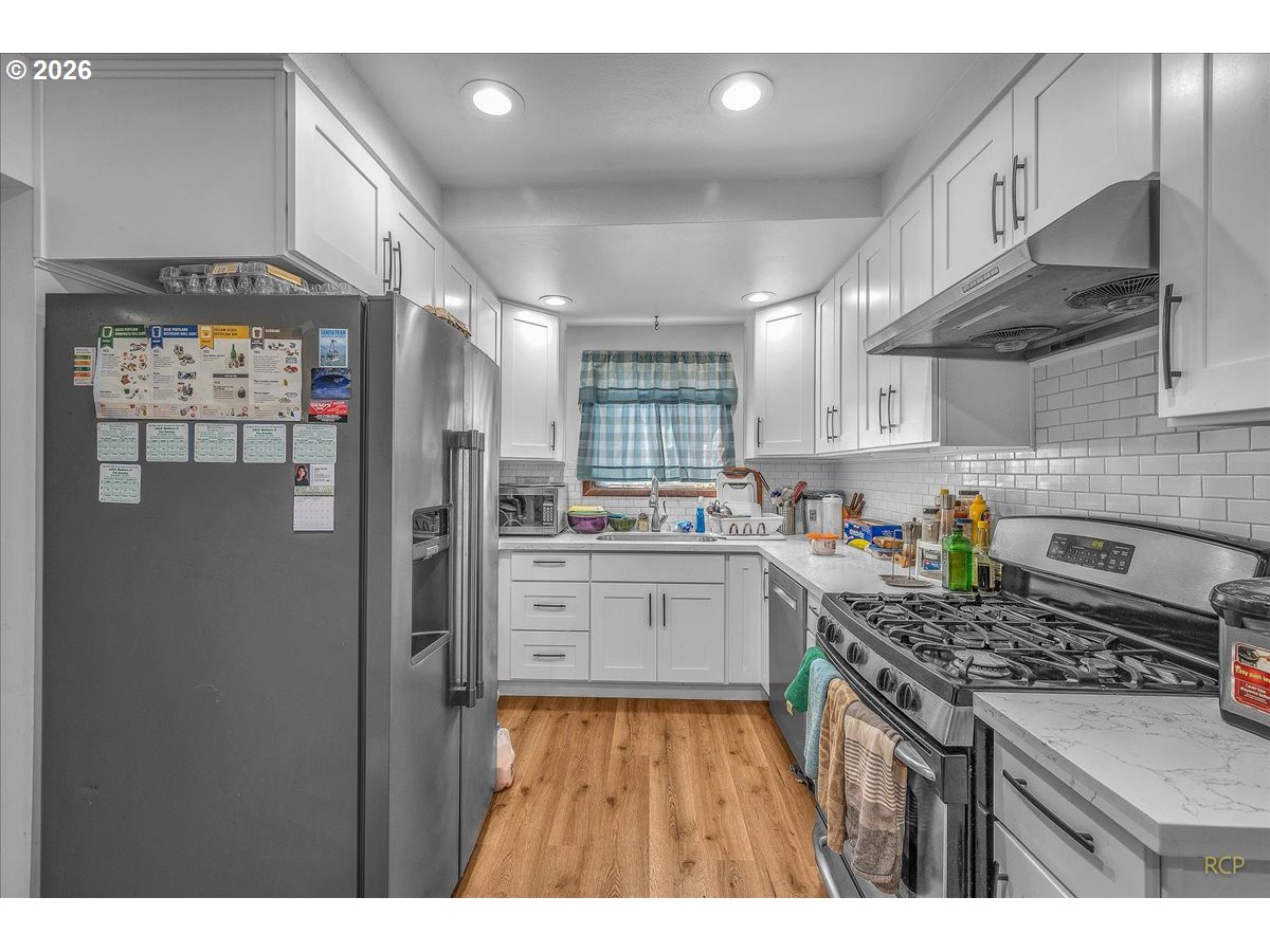 240 Northeast 80th Avenue Portland, OR 97213 - Photo 5 of 25 a kitchen with stainless steel appliances granite countertop a refrigerator a sink dishwasher a stove and white cabinets with wooden floor
