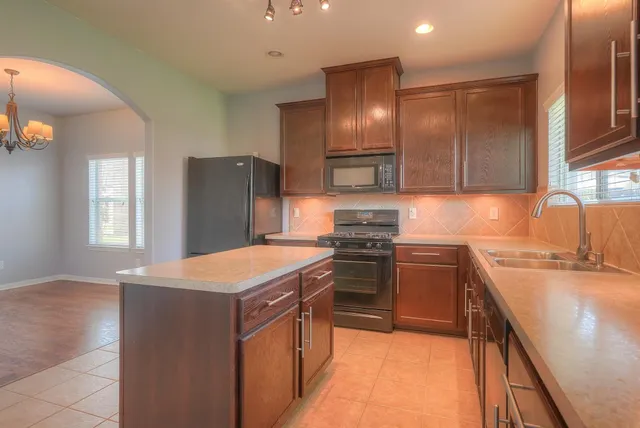 a kitchen with stainless steel appliances granite countertop refrigerator stove top oven and sink