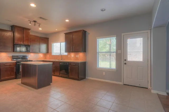 a kitchen with stainless steel appliances granite countertop a stove a sink and a refrigerator