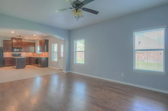 an empty room with wooden floor and windows