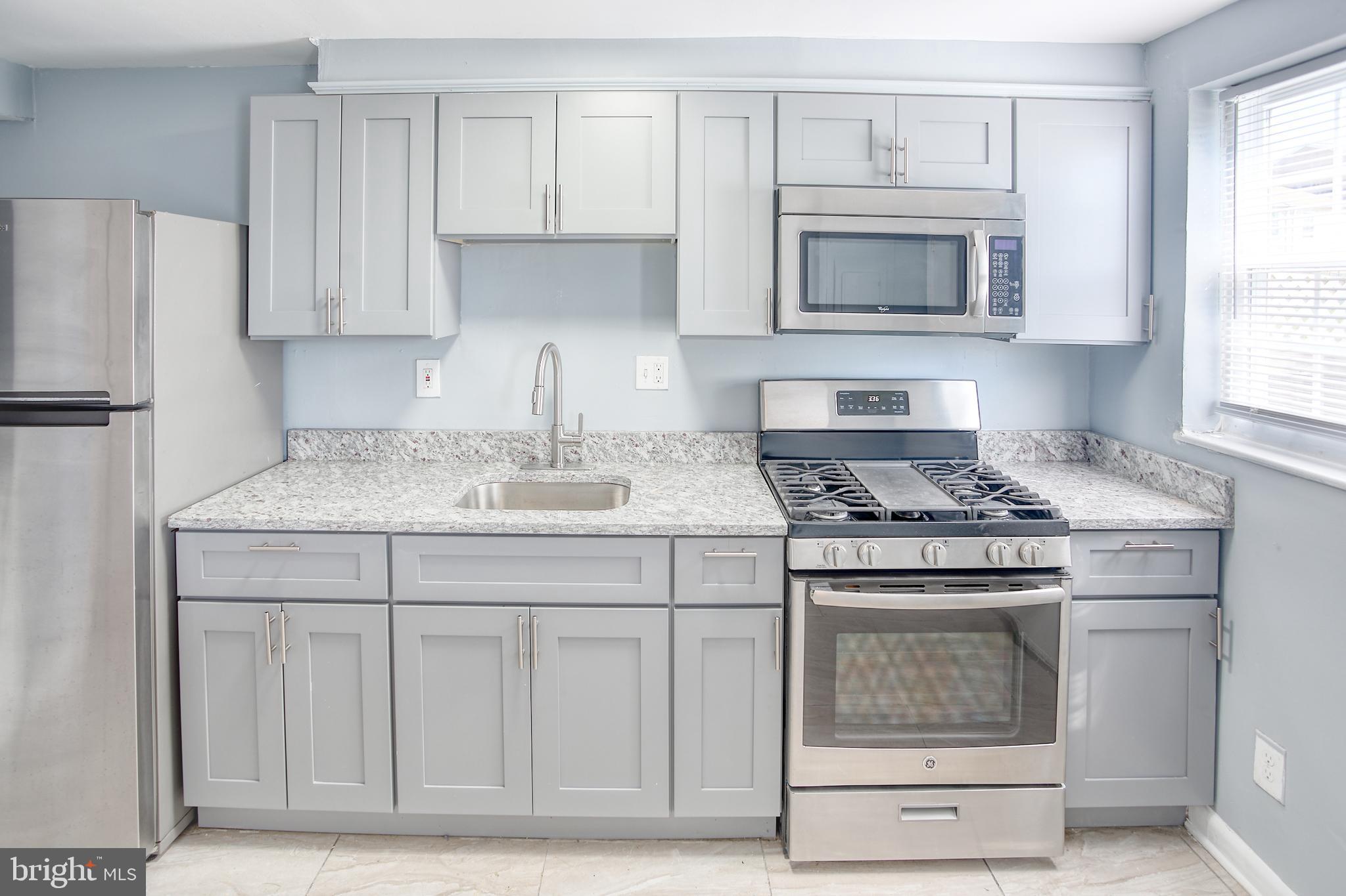 819 Aisquith Street Baltimore, MD 21202 - Photo 7 of 26 a kitchen with granite countertop white cabinets and stainless steel appliances