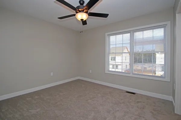 an empty room with windows and chandelier fan