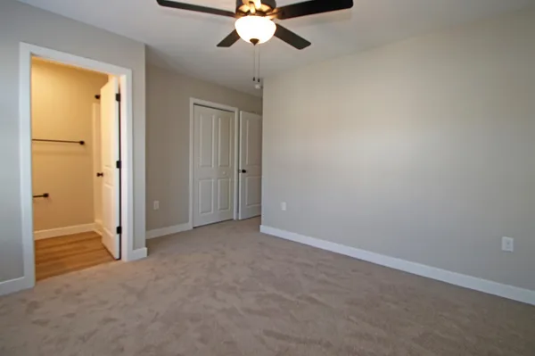 an empty room with chandelier fan and windows