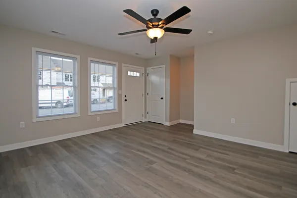 a view of an empty room with window and wooden floor