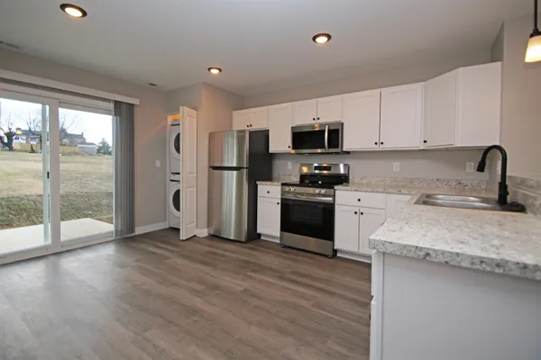 a kitchen with a sink a counter top space stainless steel appliances and a large window