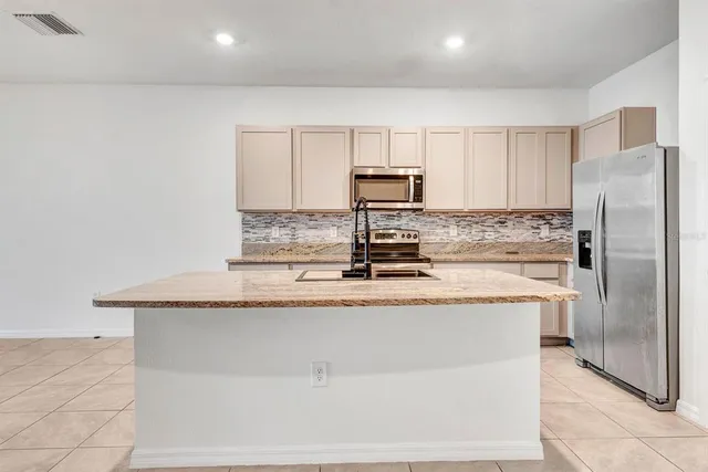 a kitchen with stainless steel appliances granite countertop a stove top oven a sink a counter top space cabinets and a window