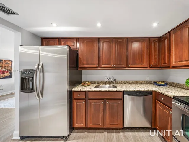 a kitchen with stainless steel appliances granite countertop a refrigerator a sink a stove a microwave and island