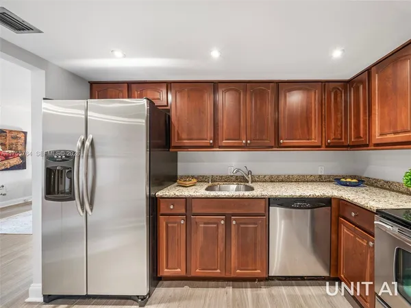 a kitchen with stainless steel appliances granite countertop a refrigerator and a sink