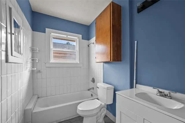 a bathroom with a toilet sink vanity tub and mirror