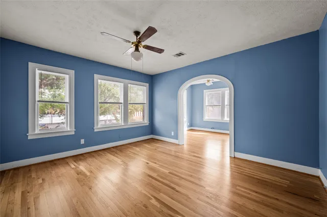 a view of an empty room with window and wooden floor