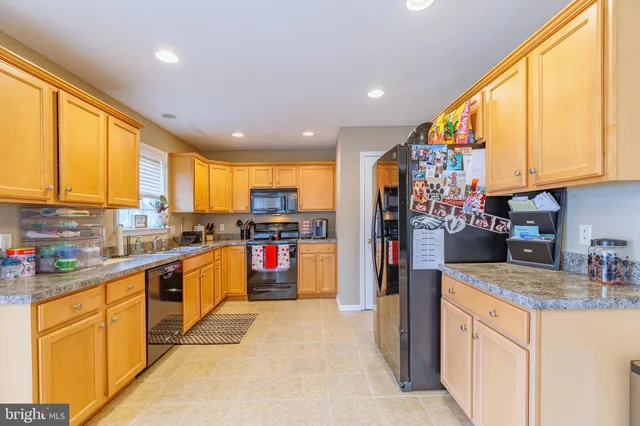 a kitchen with stainless steel appliances granite countertop a refrigerator a sink dishwasher a stove and white countertops with wooden floor