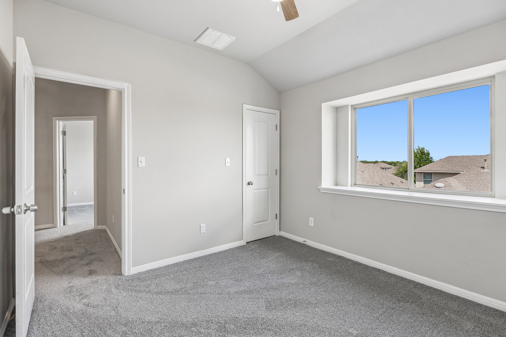 689 Nautical Loop Kyle, TX 78640 - Photo 26 of 34 A well-lit bedroom features vaulted ceilings, plush carpeting, and generous natural light from a broad window.