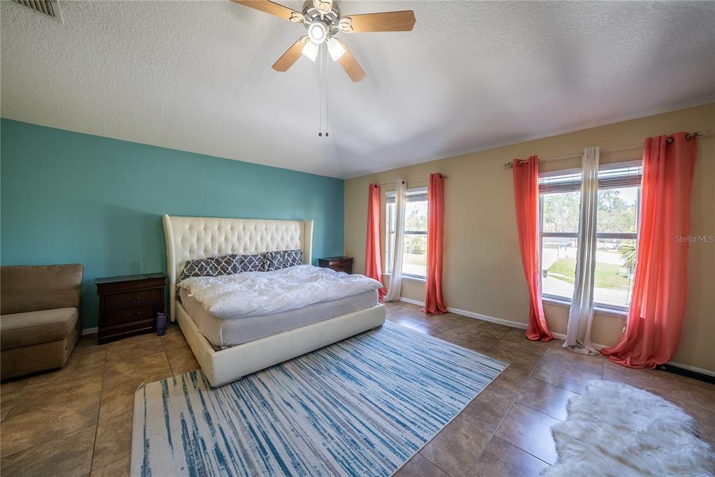 5306 Southwest 115th Street Road Ocala, FL 34476 - Photo 36 of 56 a bedroom with a large bed and a chandelier